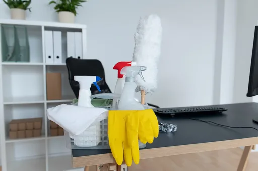 Cleaning supplies and gloves on an office desk